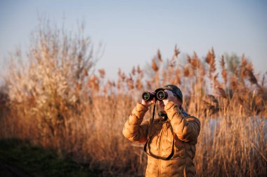 Kuş izleme. Dürbünlü kadın biyolog doğal yaşam ortamında vahşi hayvan ve su kuşlarını gözlemliyor.