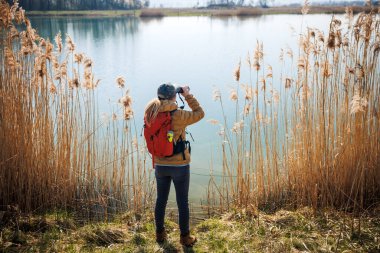 Kuşbilim ve vahşi yaşam gözlemi. Dürbünlü kadın kaşif gölde kuşları ve hayvanları izliyor.