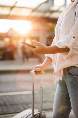 Mobil uygulamalı akıllı telefon kullanan bir kadın çevrimiçi ulaşım bileti alıyor. İstasyonda tramvay veya otobüs bekleyen bir turist. Şehirde seyahat ve toplu taşıma.