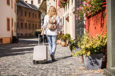 Çek Cumhuriyeti 'nin Olomouc şehrinde çantalı ve sırt çantalı bir kadın turist sokakta yürüyor. Solo gezgin