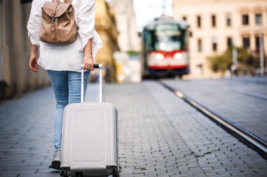 Yalnız gezgin. Sırt çantalı kadın turist bavulunu çekiyor ve sokakta yürüyor. Avrupa 'da seyahat ve tatil