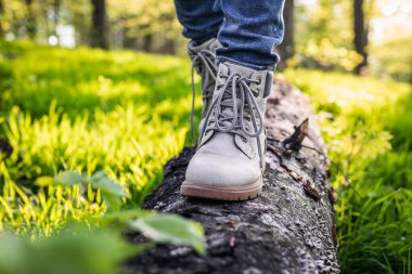 Ormanda ağaç gövdesinde yürüyen yürüyüş botlu bir turist. Doğada aktif yaşam tarzı. Deri çizmeler.