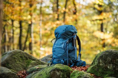 Ormanda kayalıklarda yürüyüş yapmak. Mavi sırt çantası, yürüyüş ekipmanları ve açık hava malzemeleri.