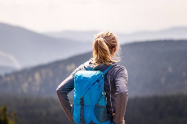 Dağ yürüyüşü. Turistler doğanın manzarasının tadını çıkarıyorlar. Sırt çantalı kadın dağın zirvesinde duruyor. Seyahat yaşam tarzı ve macera konsepti