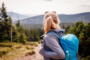 Dağ yürüyüşü. Turistler doğanın manzarasının tadını çıkarıyorlar. Sırt çantalı bir kadın sıradağlara bakıyor. Aktif yaşam tarzı ve macera konseptiyle seyahat et