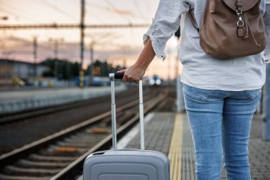 Bavullu kadın turist tren istasyonunda tren bekliyor. Tek başına seyahat kavramı