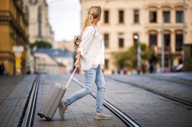 Bavul ve sırt çantalı kadın gezgin caddede yürüyor. Çek Cumhuriyeti 'nin Olomouc kentinde seyahat ve tatil