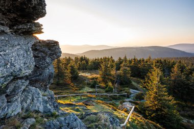 Çek Cumhuriyeti 'nin Jeseniky Dağları' ndaki doğal parklarda Vozka olarak bilinen dağ zirvesinden bir görüntü. Doğada gün doğumu. Ormanda ve tepelerde kaya oluşumunun yanında yol alıyoruz.