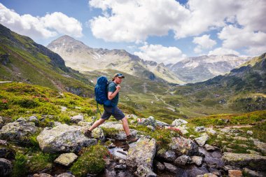 Avrupa Alpleri, Styria, Avusturya 'da yürüyüş turu sırasında sırt çantalı bir yürüyüşçü dağ akıntısını geçiyor. Yürüyüş yolunda açık hava macerası