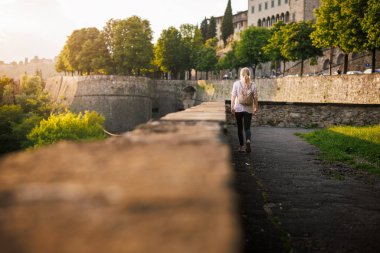 Günbatımında İtalya, Bergamo 'nun Venedik duvarları boyunca yürüyen kadın turist. Avrupa gezisi sırasında şehir molası