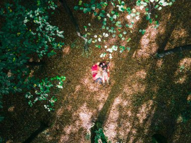 Birbirini seven çift ormanın ortasında battaniyeye uzanıyor.