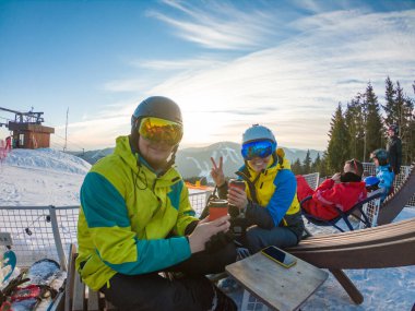Çift tepenin üstünde dinleniyor ve sıcak çay içiyor. Snowboard kayak yaşam tarzı