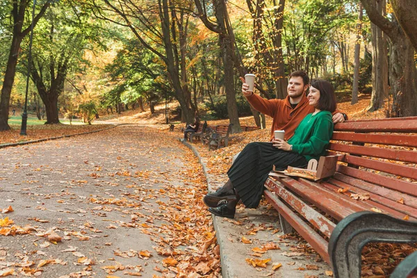 Couple Sitting Public Park Bench Autumn Sunny Day Pointing Copy — Stock Photo, Image