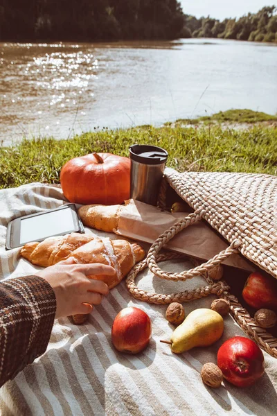 Woman hand taking muffin on picnic at river beach — Stock Photo, Image