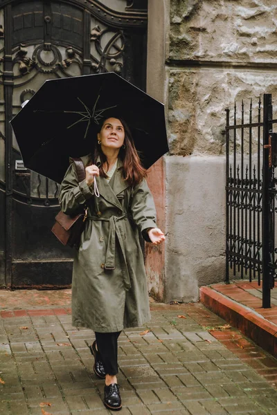 Молода красива жінка виходить з дому дощова погода відкриває парасольку — стокове фото