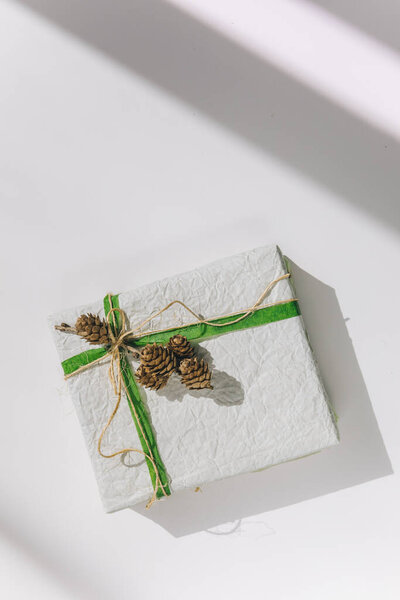 present gift box wrapped with white paper and green ribbon top view
