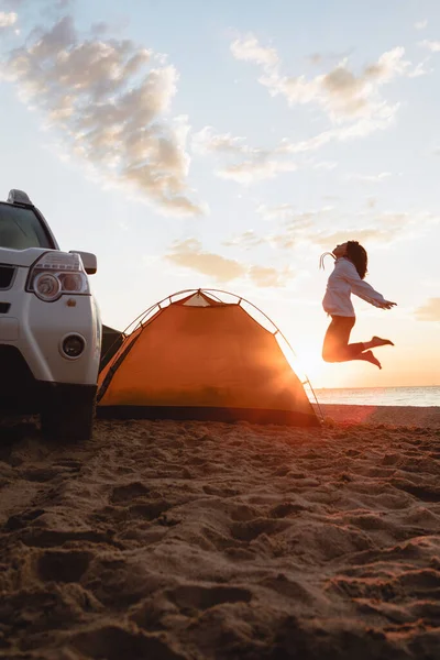 Mujer Saltando Cerca Tienda Campaña Amanecer Coche Suv Playa Arena — Foto de Stock