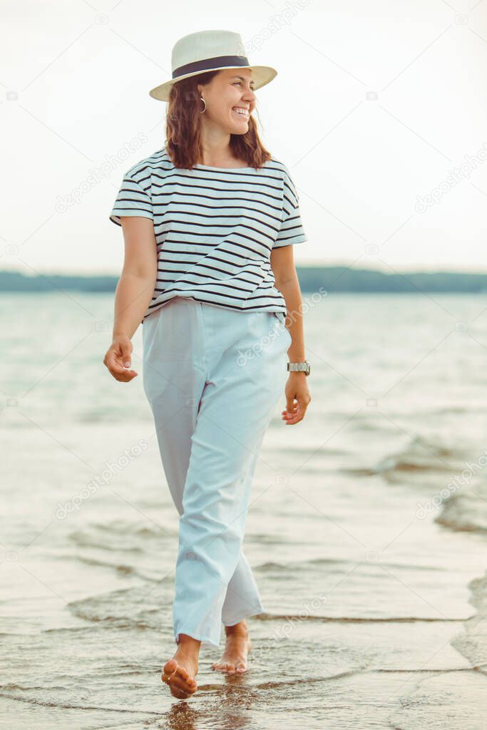 woman in white clothes walking by sea beach summer time