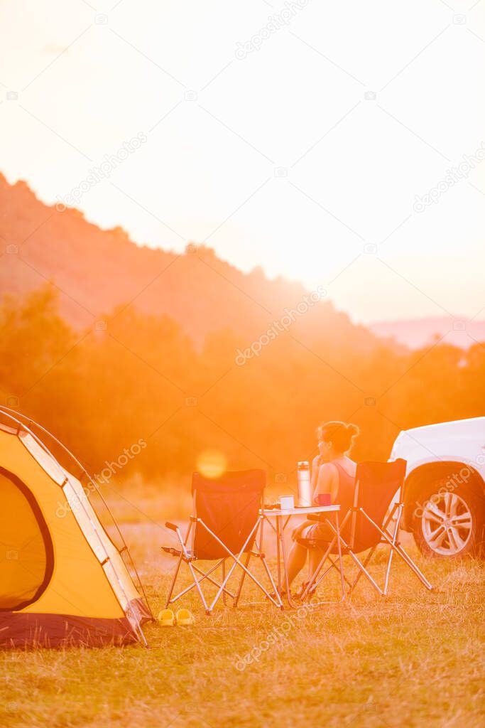 woman looking at sunset above mountains river. camping concept. copy space
