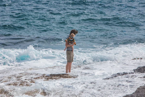 PULA, CROATIA - May 20, 2019: young father holding kid on hands showing waves in sea — Foto Stock