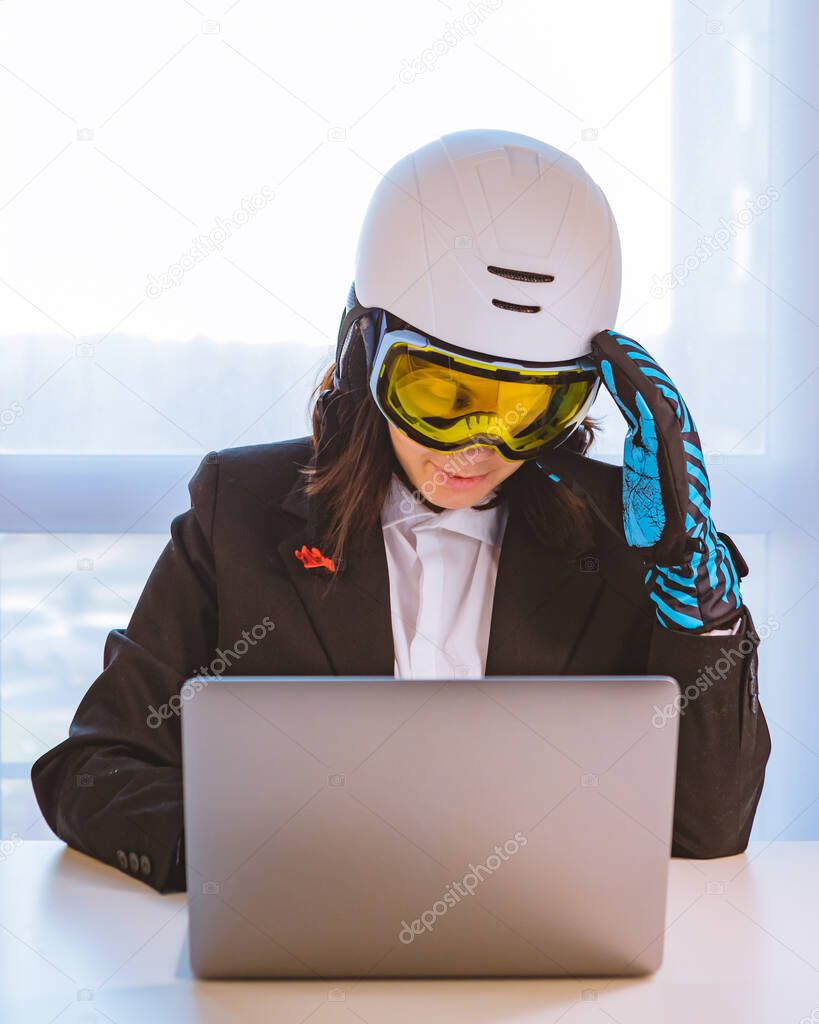 woman in ski equipment working on laptop in office dreaming about winter vacation