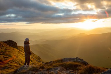 Dağların tepesinde gün batımını seyreden adamın silueti. yürüyüş kavramı