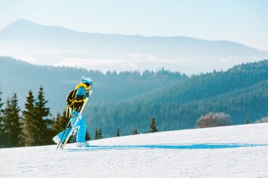Kadın arka planda kış yamaçlarında kayak yapıyor.
