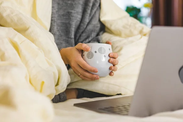 Woman hands close up holding mug of coffee near laptop — Stock Photo, Image