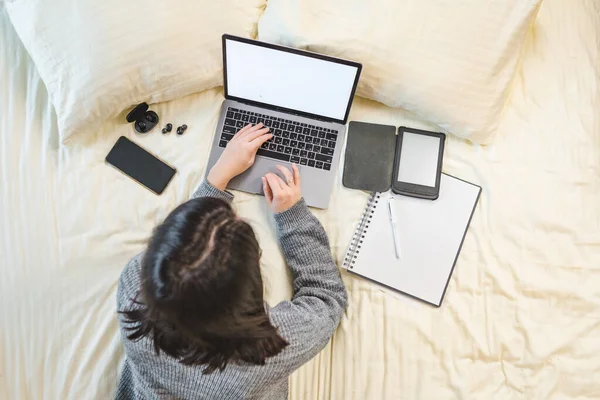 Mulher que trabalha estudando no laptop que coloca na vista superior da cama — Fotografia de Stock
