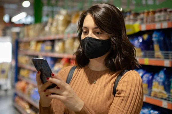 Retrato de mulher no supermercado com máscara com telefone — Fotografia de Stock