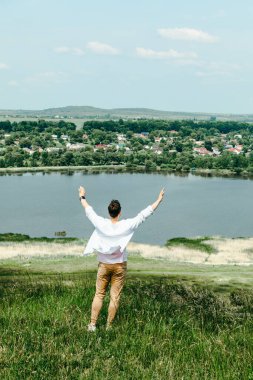 Genç, gülümseyen bir adam uçurumun kenarında rüzgarı yakalıyor. kopyalama alanı. yaz zamanı