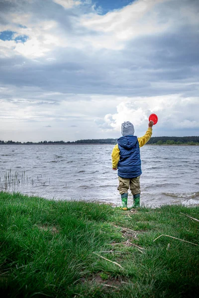 little kid throwing rocks in lake. rubber boots. copy space