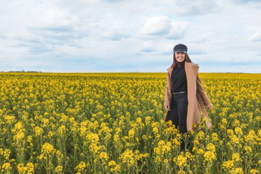 Sarı kolza tohumu tarlasında yürüyen güzel bir kadın. Boşluğu kopyala