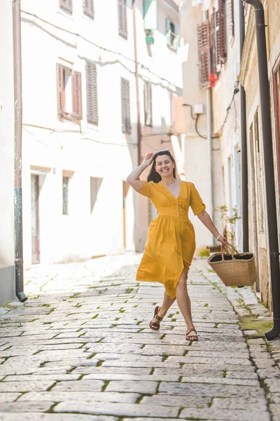 黄色のドレスの女性と少しわらの帽子クロアチアの古い観光地の詩の街を歩く — ストック写真