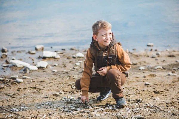 Niño pequeño en la playa meciendo rocas en el agua — Foto de Stock