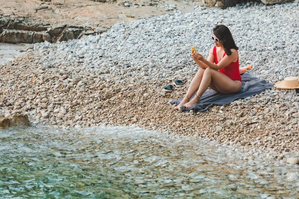 Giovane Bella Donna Costume Bagno Rosso Seduta Sulla Spiaggia Rocciosa — Foto Stock