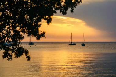 Deniz koyunda günbatımı ve arka planda yatlar. Boşluğu kopyala