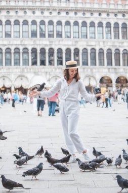 Beyaz şapkalı kadın Venice City Meydanı San Marco 'da güvercinlerle eğleniyor.