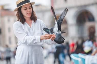 Beyaz şapkalı kadın Venice City Meydanı San Marco 'da güvercinlerle eğleniyor.