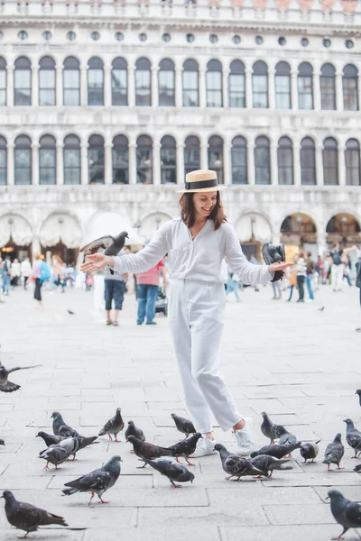 Beyaz şapkalı kadın Venice City Meydanı San Marco 'da güvercinlerle eğleniyor.