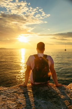man with backpack enjoying sunset over the sea
