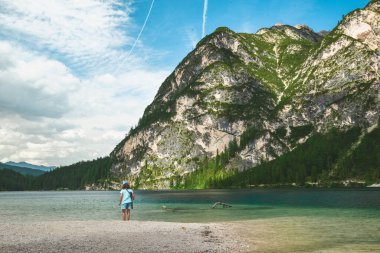little girl walking by beach of lake in mountains