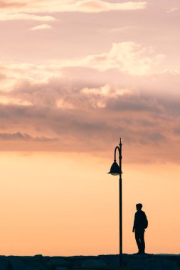 Günbatımında şehir çakmağı olan pembe bulutlu bir adamın silueti. Boşluğu kopyala