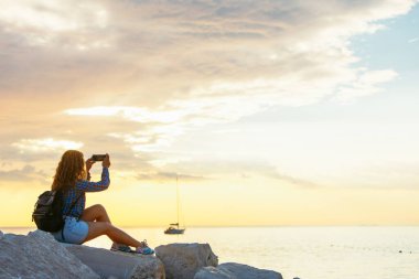 Sırt çantalı kadın gün batımını seyrediyor. Boşluğu kopyala