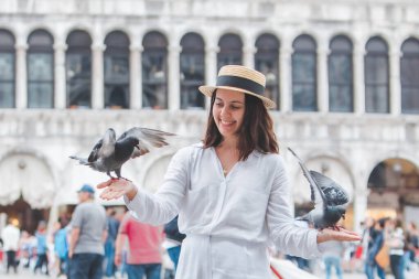 Beyaz şapkalı kadın Venice City Meydanı San Marco 'da güvercinlerle eğleniyor.