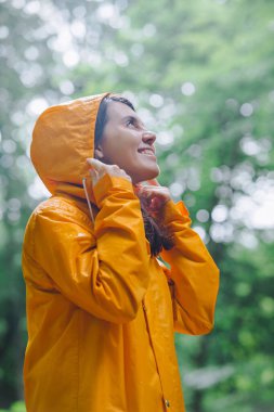 Sarı yağmurluklu kadın yağmurlu ormanda yürüyor. Dikiz aynası. kopyalama alanı. Büyük dünyadaki küçük insanlar.