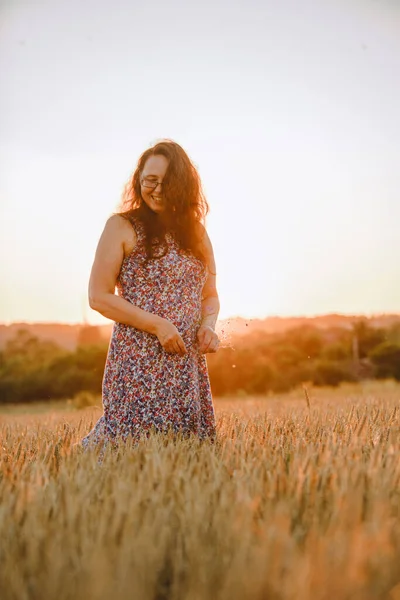 beautiful mature woman in sundress at wheat field on sunset copy space