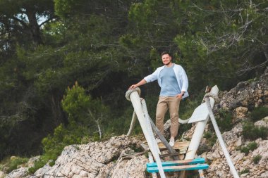 Gülümseyen adam asma köprünün yanında poz veriyor yaz zamanı