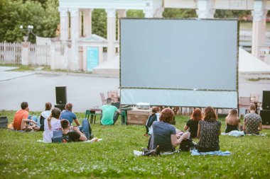 açık hava sineması konsepti. İnsanlar şehir parkında film izliyor. Boşluğu kopyala