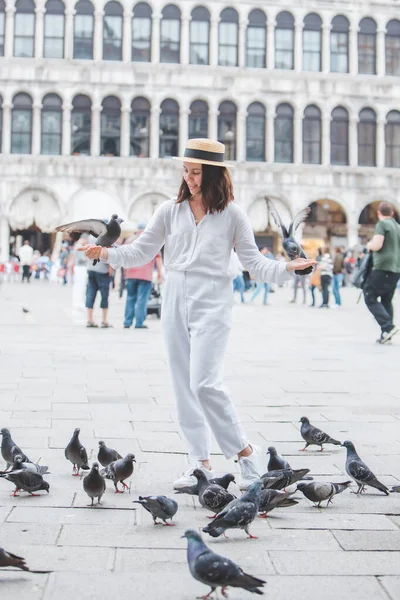 Beyaz şapkalı kadın Venice City Meydanı San Marco 'da güvercinlerle eğleniyor.